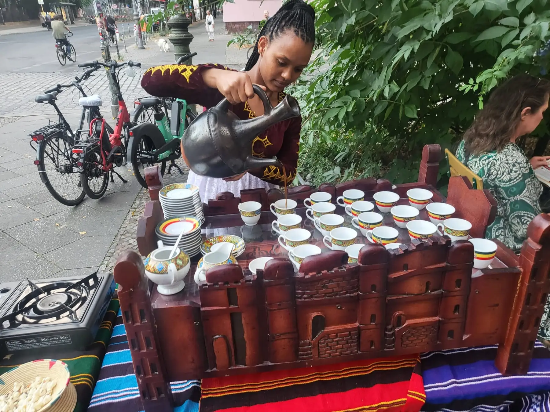 Kaffee wird aus der Jebena in eine Reihe kleiner Tassen gegossen